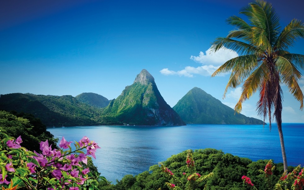 A captivating view of Saint Lucia, a small island nation in the Caribbean Sea, captured from a distance. The image showcases the lush green landscape of the island, which is dotted with small villages, resorts, and beaches. The island's mountainous terrain is visible in the background, providing a stunning backdrop for the scene.