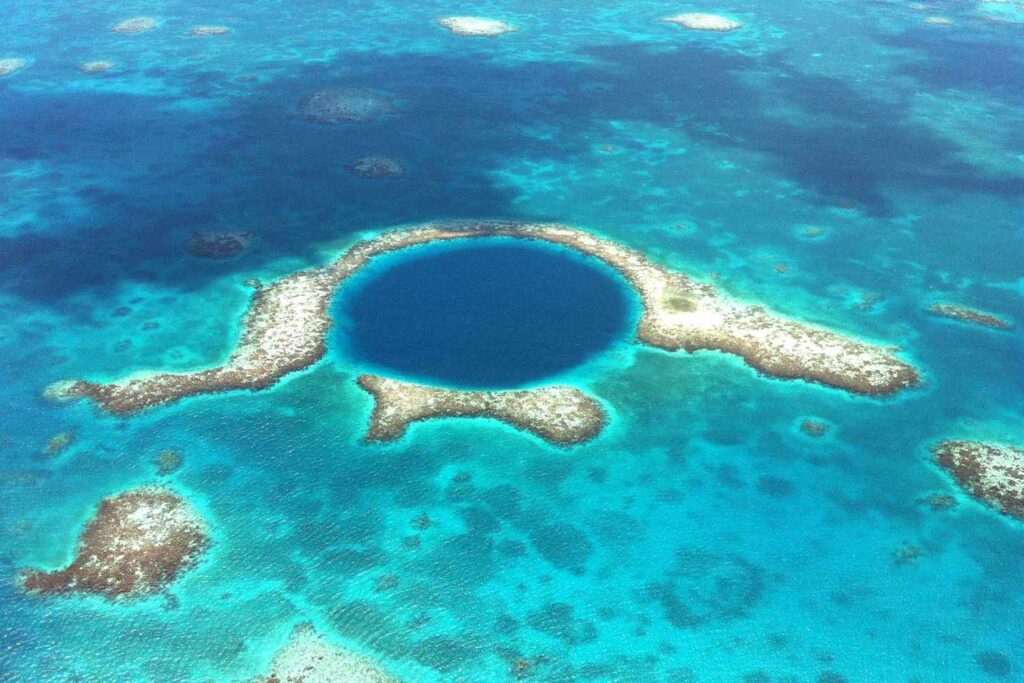 A captivating view of the Great Blue Hole, a world-famous underwater sinkhole situated off the coast of Belize. The image showcases the deep blue color of the hole, contrasting with the turquoise hues of the surrounding Caribbean Sea.