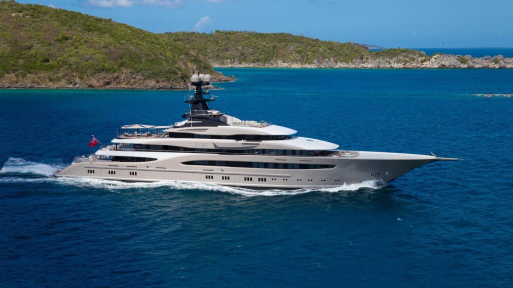 Motor Yacht Kisemt underway cruising through the ocean with a wake behind it and green headland behind it