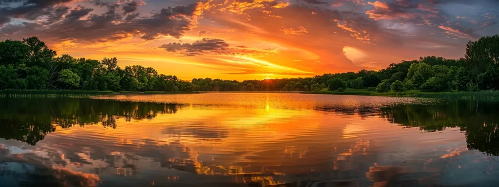 a breathtaking sunrise casts a warm golden glow over a serene lake, reflecting the vibrant colors of the sky amidst lush, verdant trees.